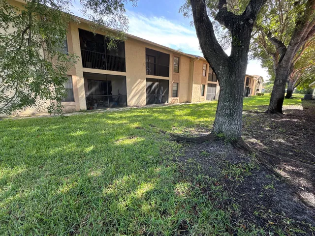 a front view of a house with garden and tree