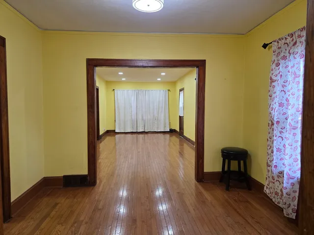 a view of a hallway with wooden floor and furniture