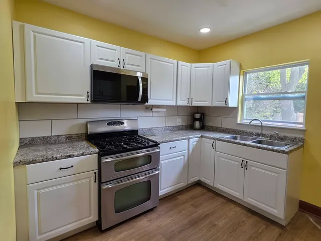 a kitchen with stainless steel appliances granite countertop a stove a sink and a microwave