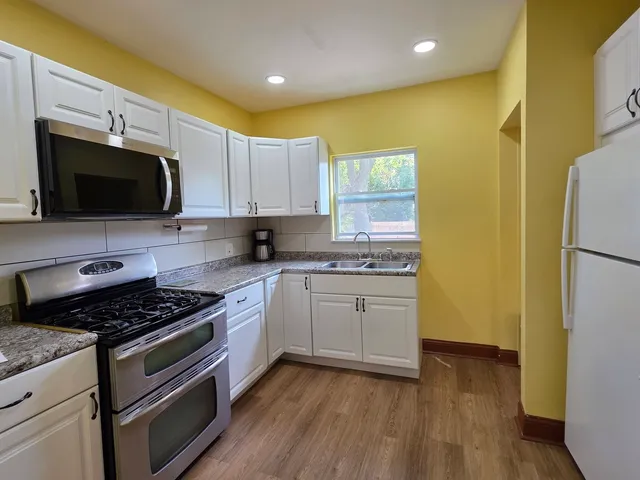 a kitchen with stainless steel appliances granite countertop a stove a sink and a refrigerator