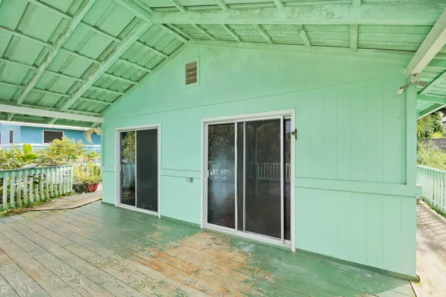a view of a brick house with large trees and plants
