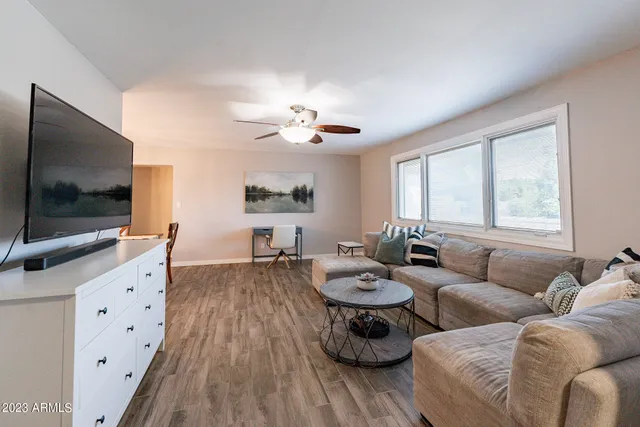 a living room with furniture a flat screen tv and a large window
