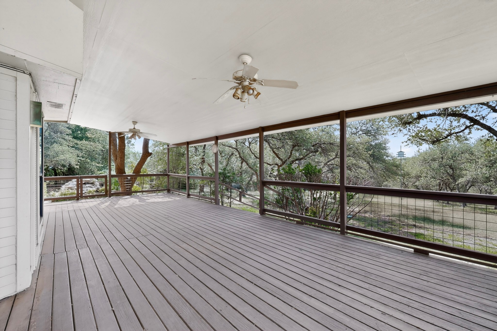 1003 Pier Branch Road Dripping Springs, TX 78620 - Photo 2 of 40 An inviting covered patio offers abundant space for outdoor living, overlooking a serene, tree-filled landscape.