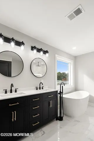 a bathroom with a double vanity sink a mirror and bathtub