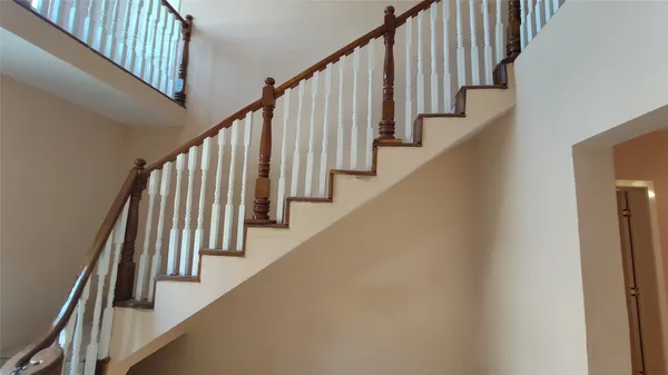 a view of staircase with lots of frames on wall and wooden floor
