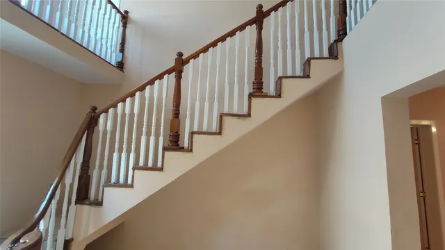 a view of staircase with lots of frames on wall and wooden floor