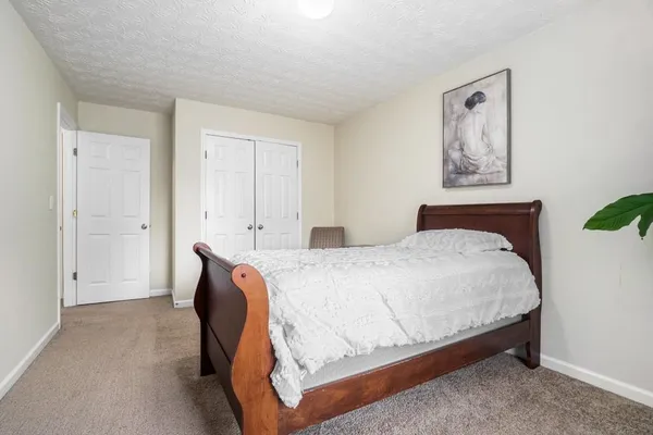 a spacious bedroom with a bed and painting on the wall