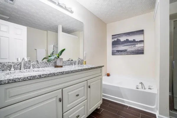 a bathroom with a granite countertop tub sink and mirror
