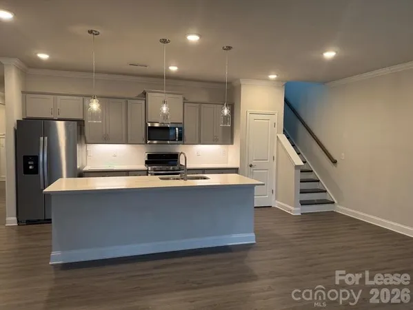 a large kitchen with stainless steel appliances a large counter top and wooden floors