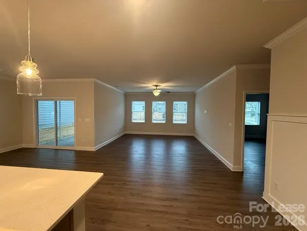 a view of an empty room with window and wooden floor
