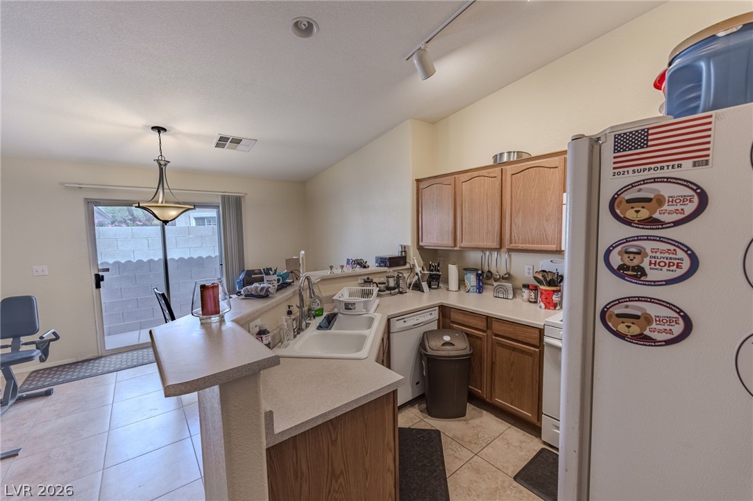 4994 Mascaro Drive Las Vegas, NV 89122 - Photo 7 of 30 A functional kitchen boasts ample counter space and warm wood cabinetry, flowing into a bright dining area with sliding glass doors.