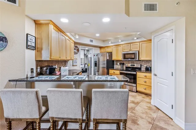 a kitchen with stainless steel appliances granite countertop a stove top oven a refrigerator a sink and a dining table with granite countertop