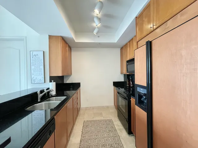 a kitchen with granite countertop stainless steel appliances a sink stove top oven and cabinets