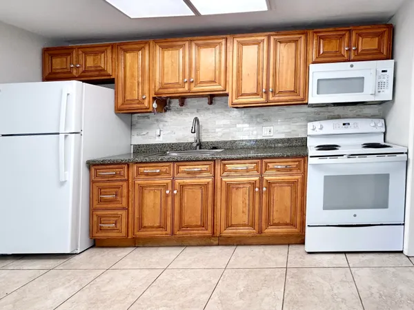 a large kitchen with granite countertop a stove a sink and a refrigerator