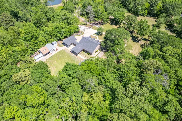 an aerial view of residential house with outdoor space and trees all around