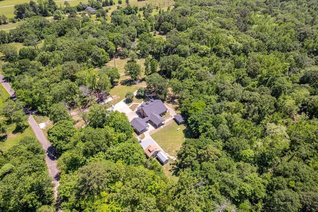 an aerial view of residential house with outdoor space and trees all around