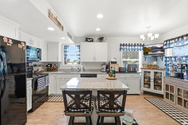 391 South 440th Street West Preston, ID 83263 - Photo 8 of 28 Kitchen featuring an island with stone-finish countertop, recessed lighting, wood-finish flooring, white cabinetry, and black appliances