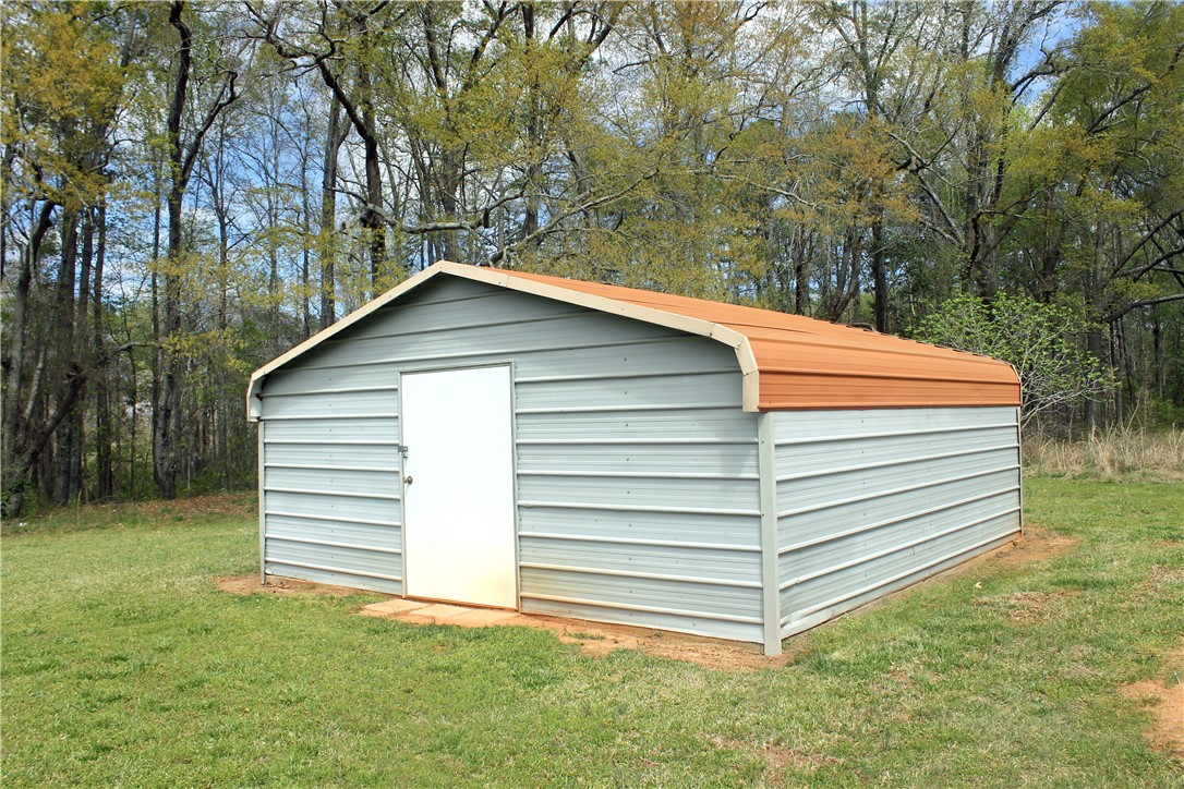 1007 O Neal Street Belton, SC 29627 - Photo 20 of 25 This outdoor shed offers ample storage space, blending functionality with a natural setting.