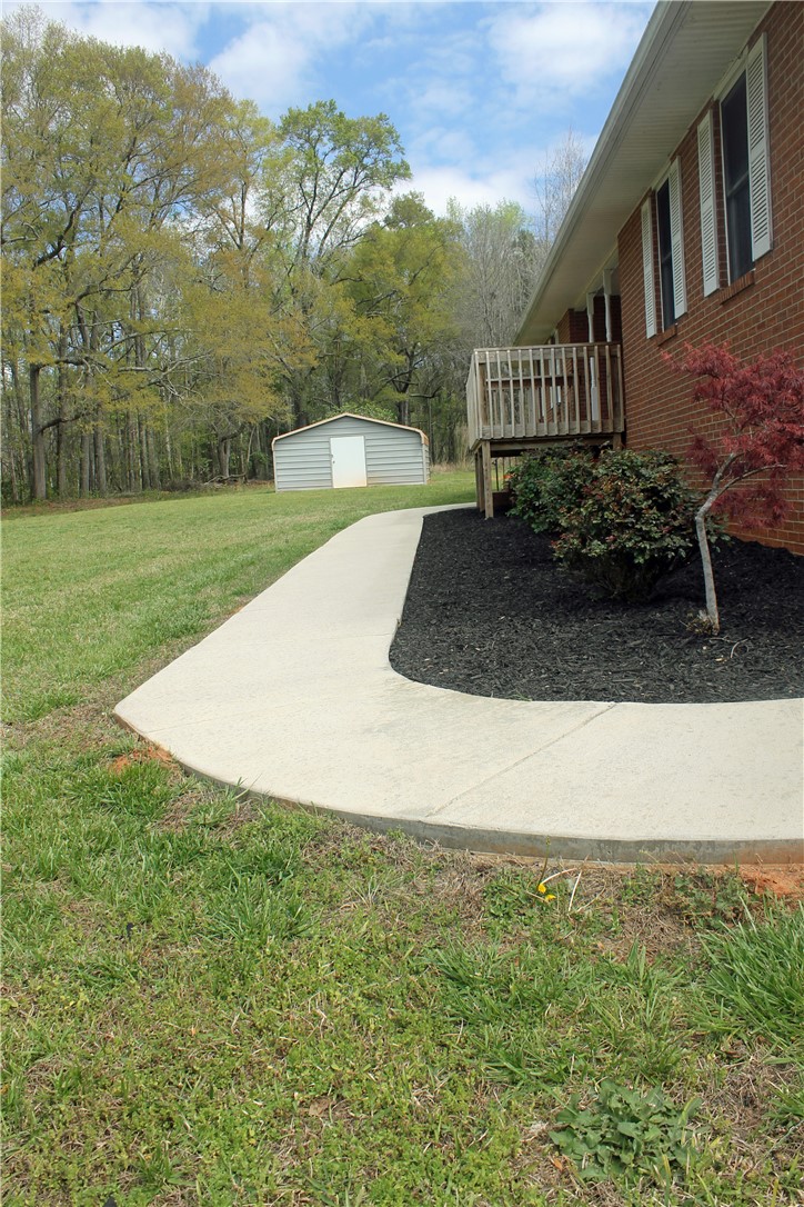1007 O Neal Street Belton, SC 29627 - Photo 4 of 25 A graceful curved walkway guides guests to this charming residence, featuring a deck and storage shed.