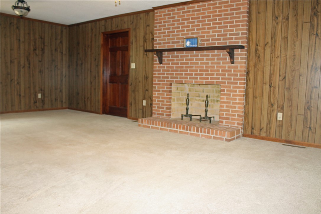 1007 O Neal Street Belton, SC 29627 - Photo 6 of 25 This inviting living space features warm wood paneling and a classic brick fireplace.