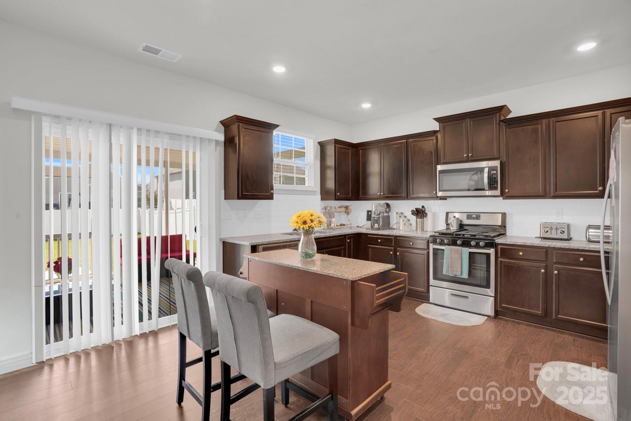 4918 Traynor Road Charlotte, NC 28216 - Photo 5 of 27 a kitchen with stainless steel appliances granite countertop a stove top oven a sink dishwasher a dining table and chairs with wooden floor