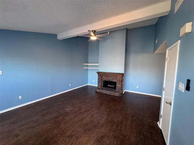 an empty room with wooden floor fireplace and windows