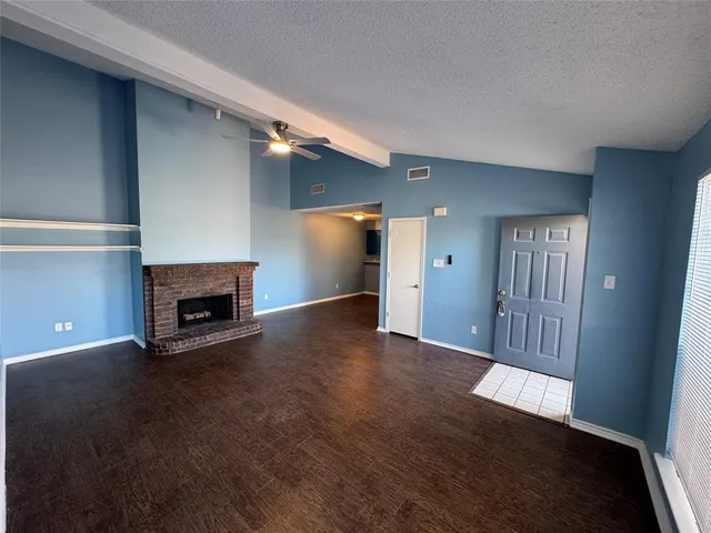 an empty room with wooden floor fireplace and windows