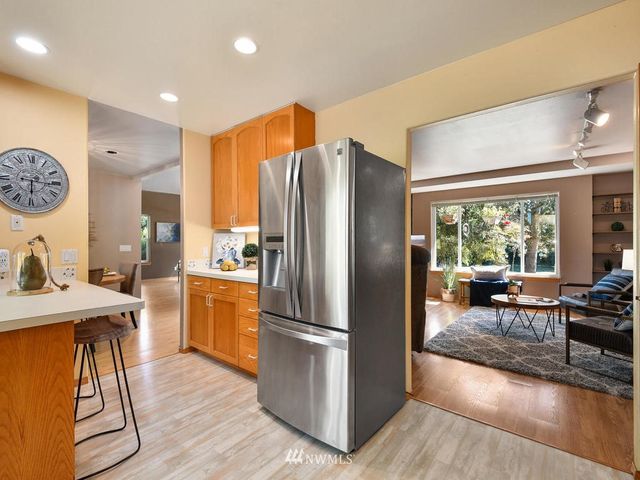 a kitchen with stainless steel appliances granite countertop a refrigerator stove top oven and couches with wooden floor