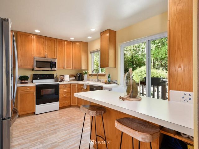 a kitchen with a sink a counter top space a large window and stainless steel appliances