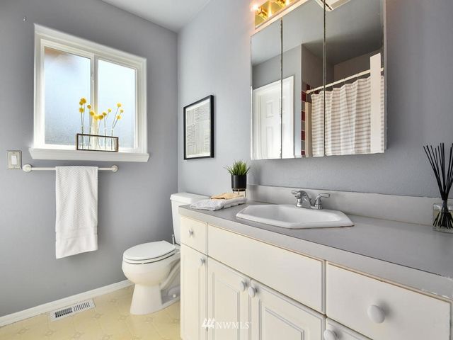 a bathroom with a granite countertop sink and a toilet