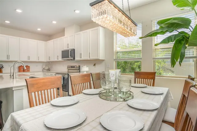 a kitchen with stainless steel appliances kitchen island granite countertop a stove a white table and chairs