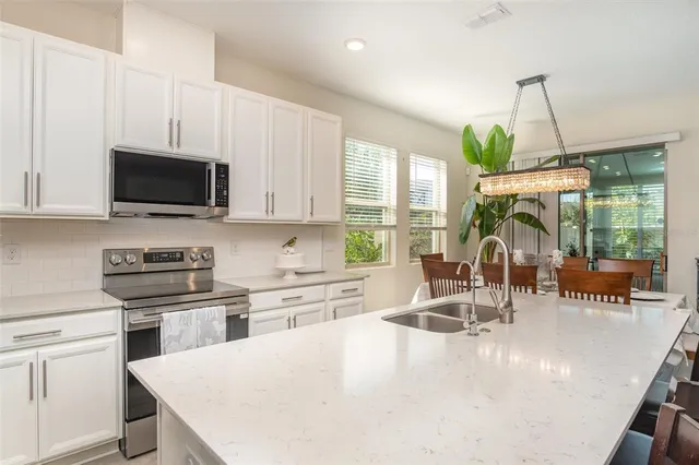 a kitchen with stainless steel appliances granite countertop a stove top oven a sink a dining table and chairs with wooden floor