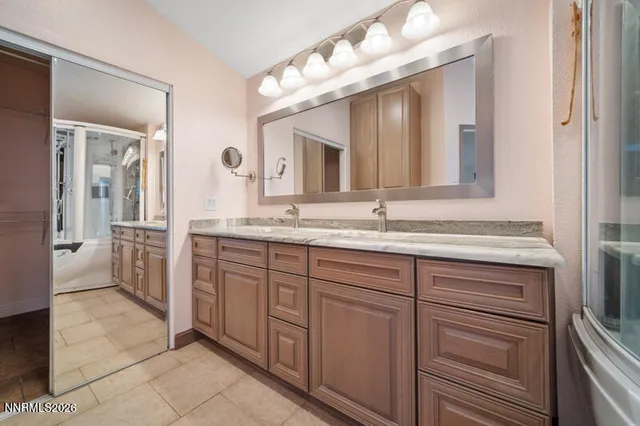 a bathroom with a granite countertop double vanity sink and a mirror