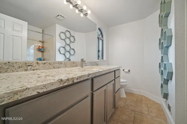 a bathroom with a granite countertop sink a mirror and shower