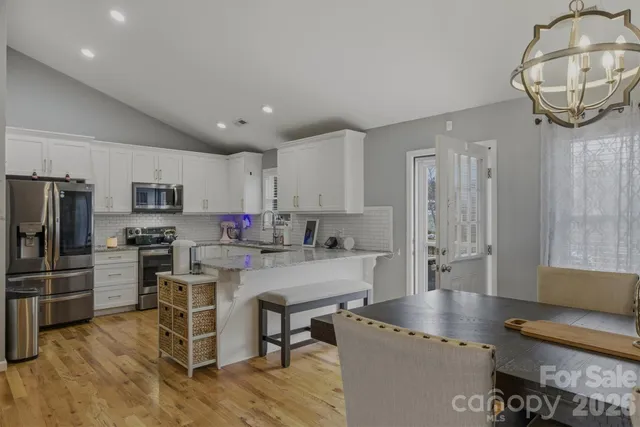 a kitchen with stainless steel appliances granite countertop a stove refrigerator and a view of living room