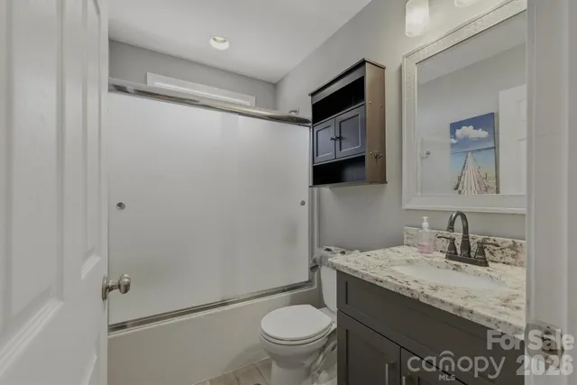 a bathroom with a granite countertop sink toilet and shower