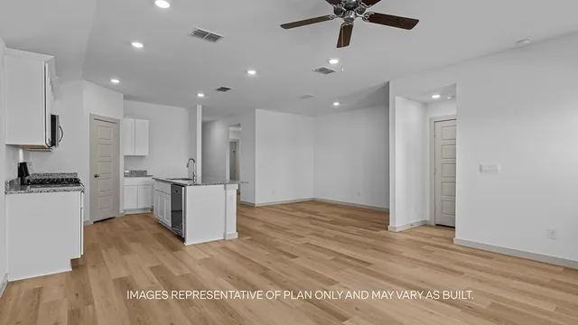 a view of kitchen and empty room with wooden floor