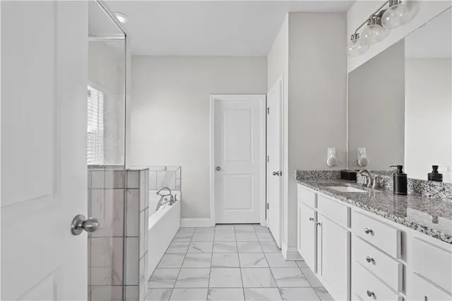a spacious bathroom with a granite countertop sink a mirror and a shower
