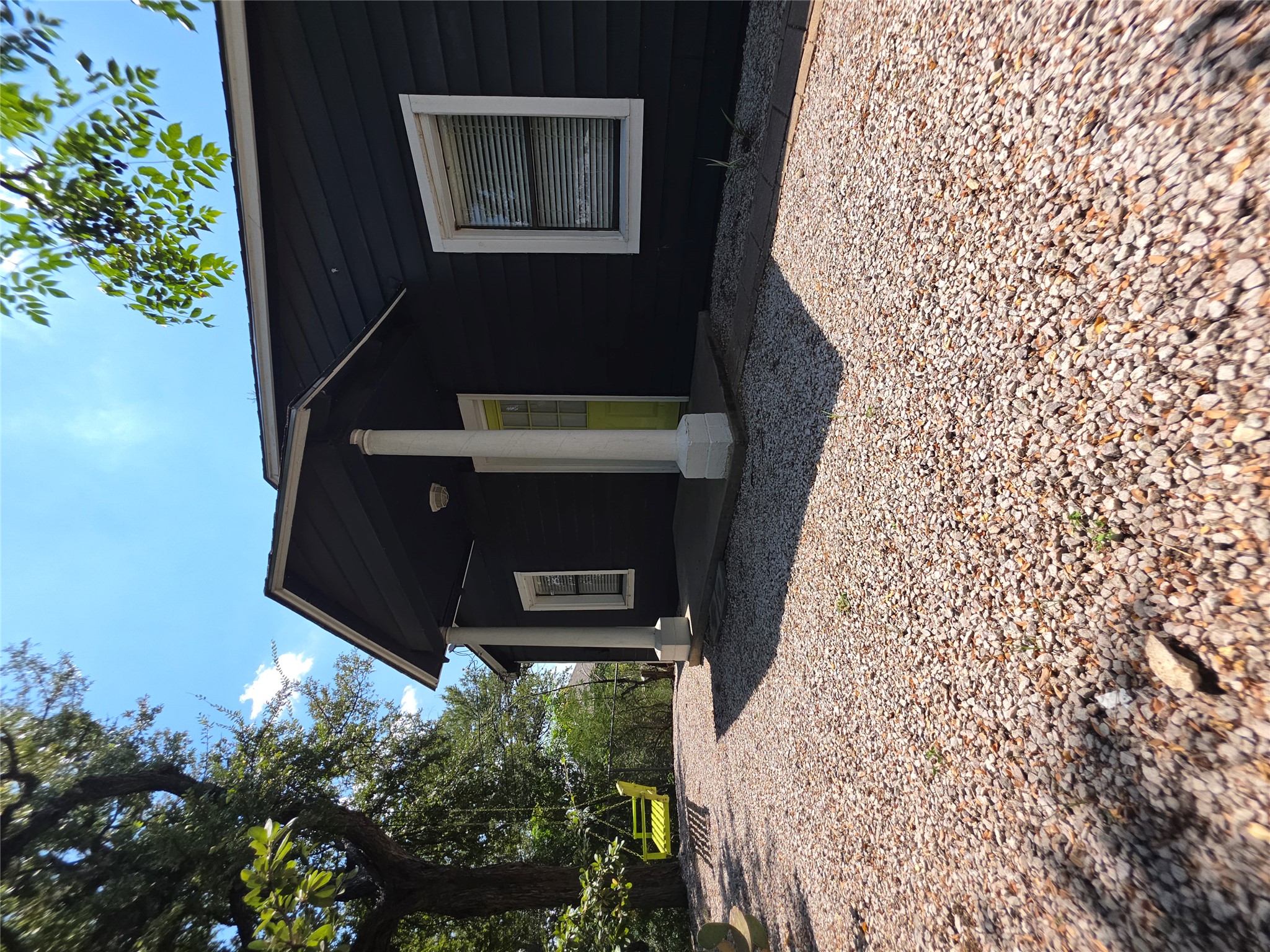 1166 Ridgeway Drive Austin, TX 78702 - Photo 3 of 22 A charming cottage exterior with a vibrant entry door, set amidst natural landscaping and a gravel path.