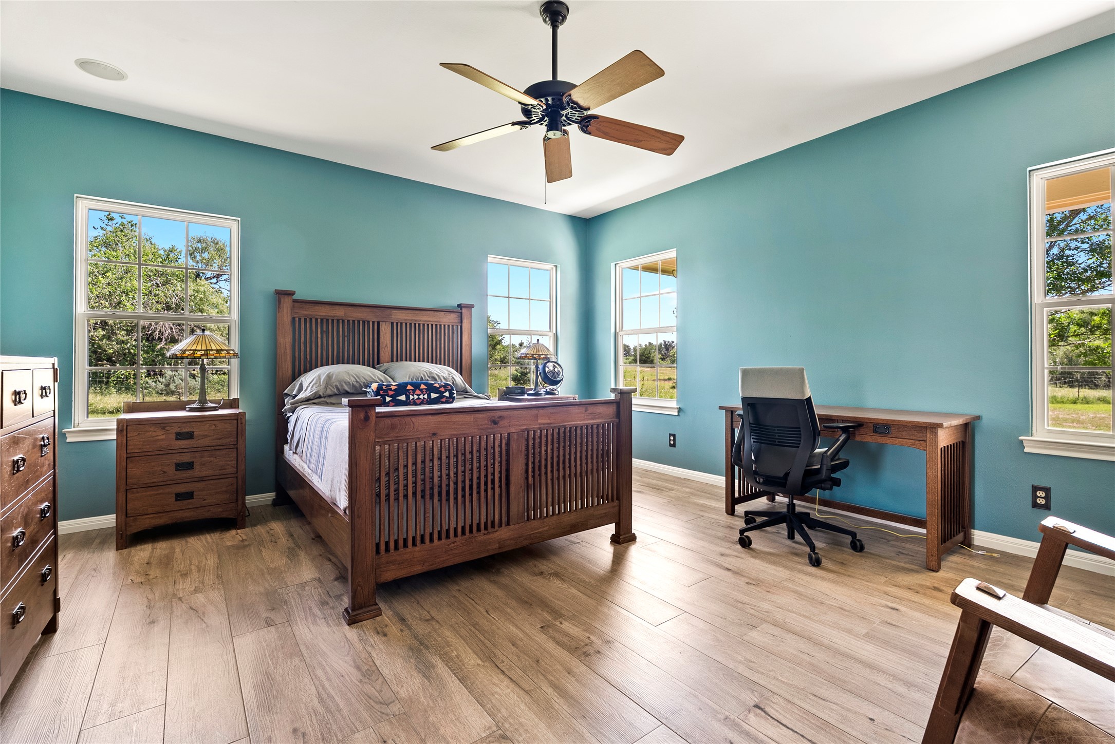 928 Upper Elgin River Road Elgin, TX 78621 - Photo 19 of 40 Spacious room featuring wood-finish flooring, light blue wall finishes, and multiple windows providing natural light.