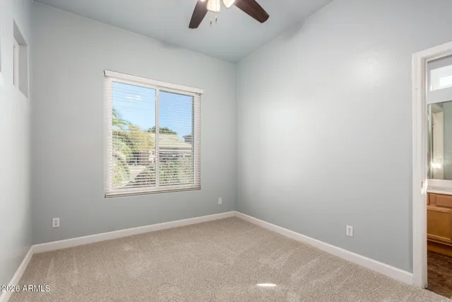 an empty room with a window and a chandelier fan