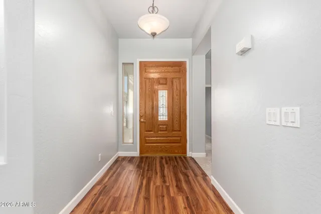 a view of a hallway with wooden floor and a bathroom