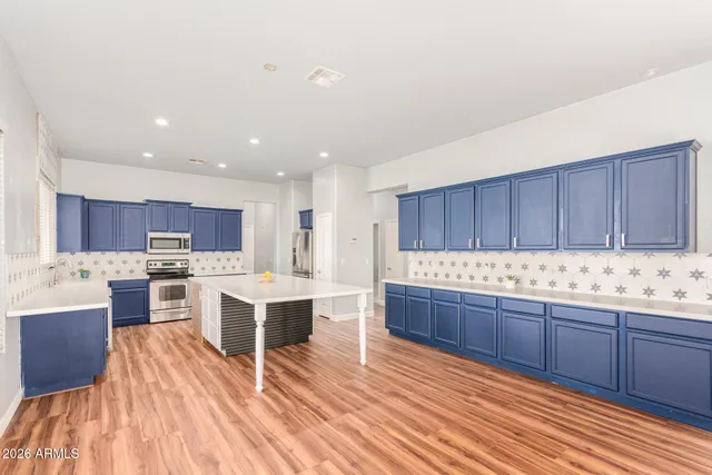 a kitchen with stainless steel appliances kitchen island granite countertop a stove refrigerator and cabinets