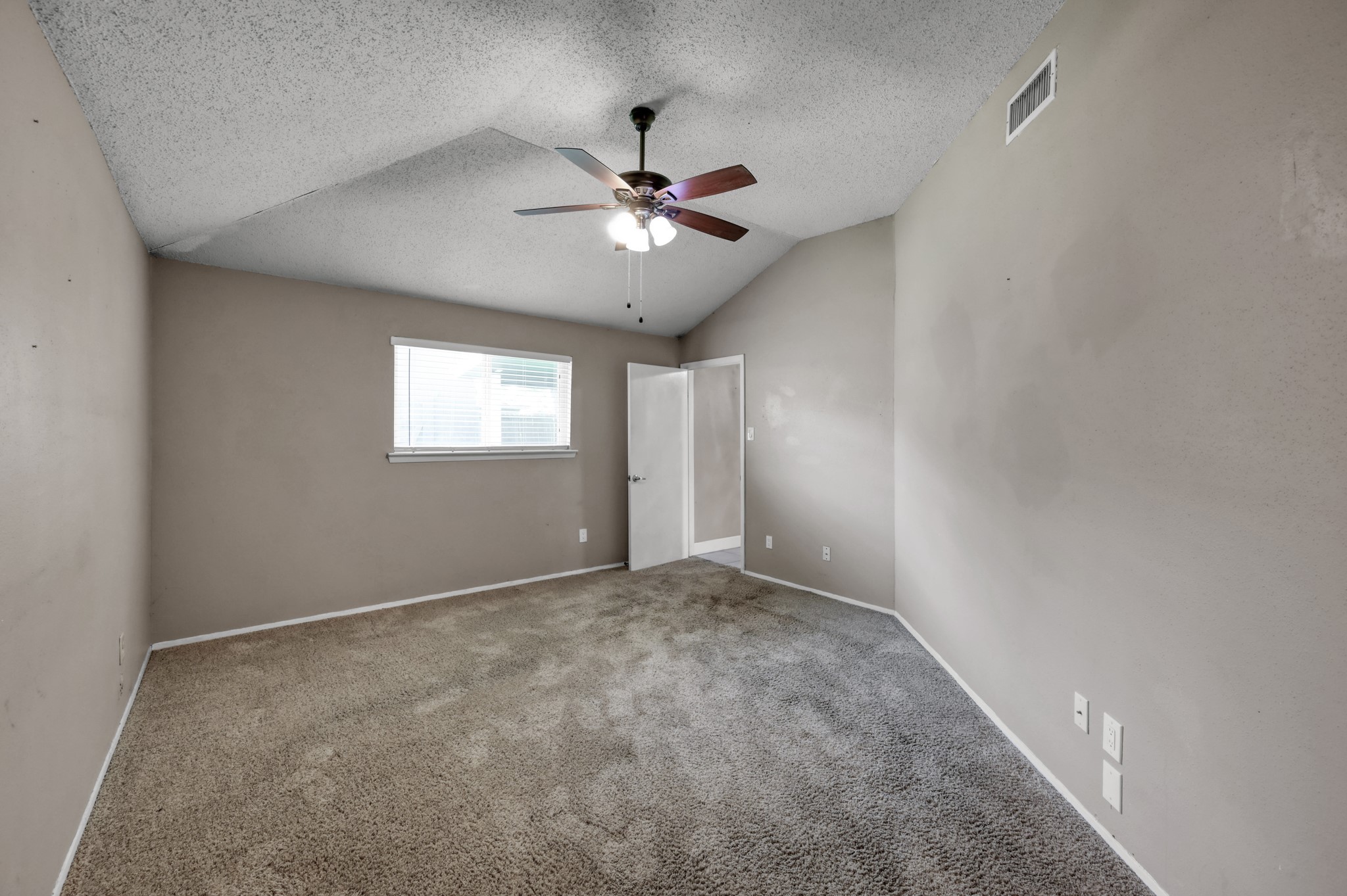 12015 Fallbrook Drive Houston, TX 77065 - Photo 17 of 29 This room features neutral-colored walls, carpeted flooring, and a ceiling fan with lights. It has a sloped ceiling, a window for natural light, and a door leading to another area, offering a cozy space for various uses.