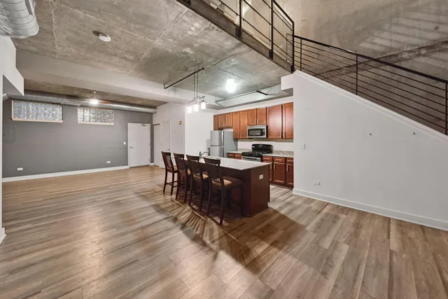 a kitchen with stainless steel appliances granite countertop a refrigerator a stove a sink dishwasher a dining table and chairs with wooden floor