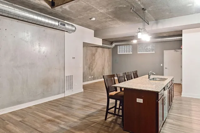 a view of a kitchen with granite countertop wooden floor a dining table and chairs