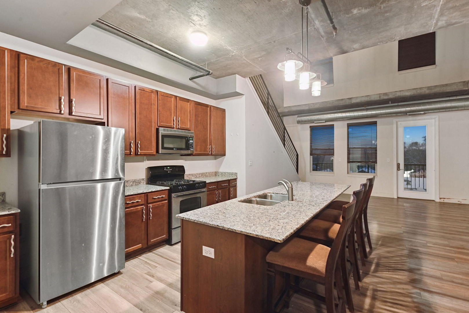 342 River Street, Unit 3402 Lemont, IL 60439 - Photo 23 of 25 a kitchen with stainless steel appliances granite countertop a refrigerator a stove a sink dishwasher a dining table and chairs with wooden floor