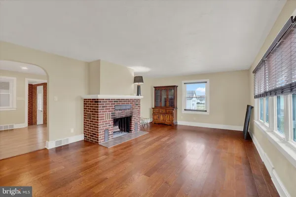 an empty room with wooden floor fireplace and windows