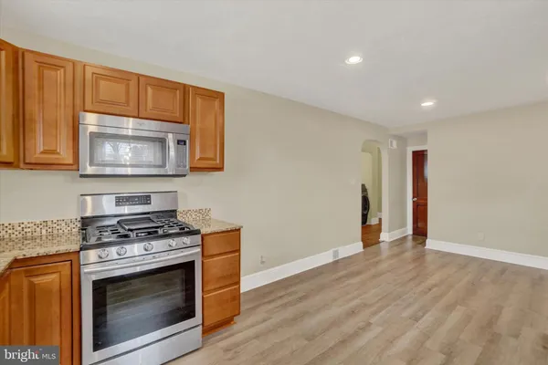 a kitchen with granite countertop wood cabinets stainless steel appliances and a wooden floor