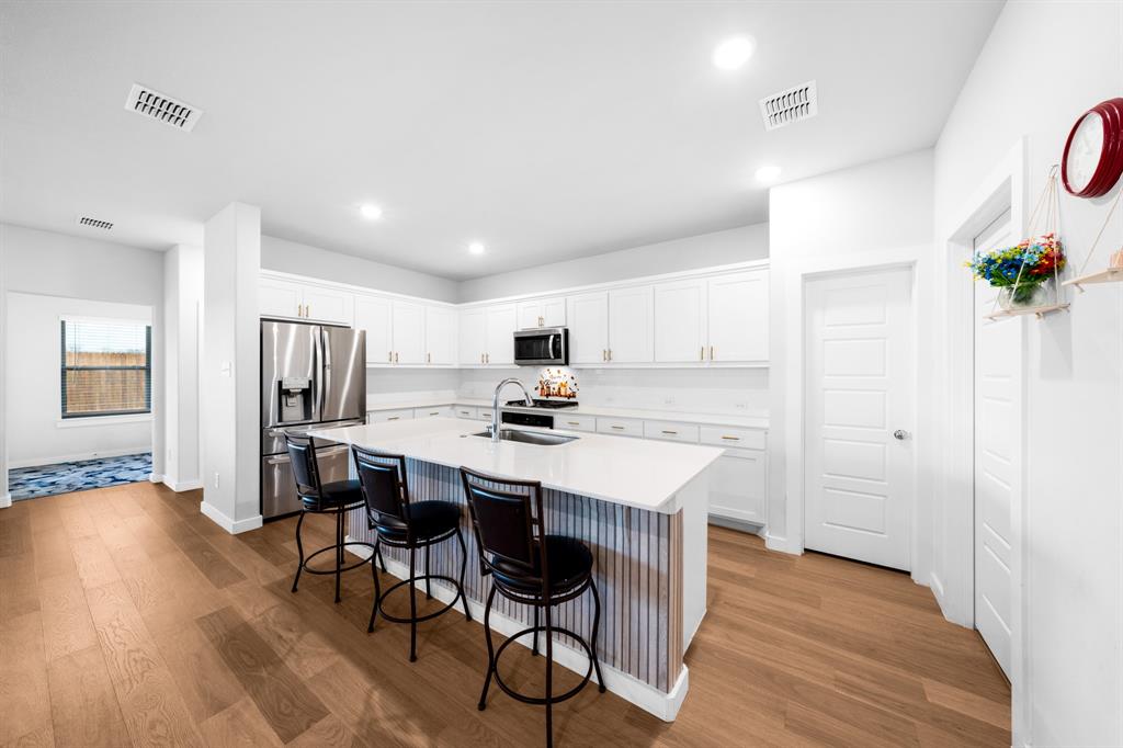 1012 Breezy Street Princeton, TX 75407 - Photo 3 of 34 a kitchen with stainless steel appliances a dining table chairs and wooden floor